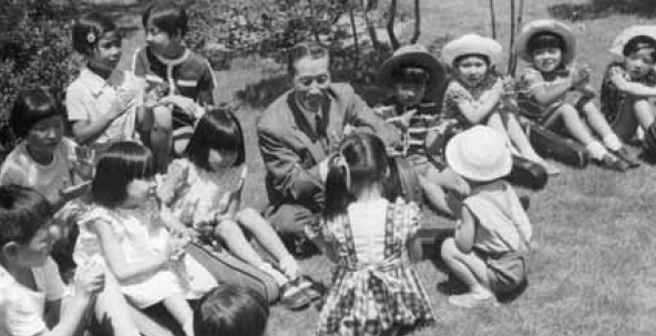 Dr. Suzuki and children sit in a circle